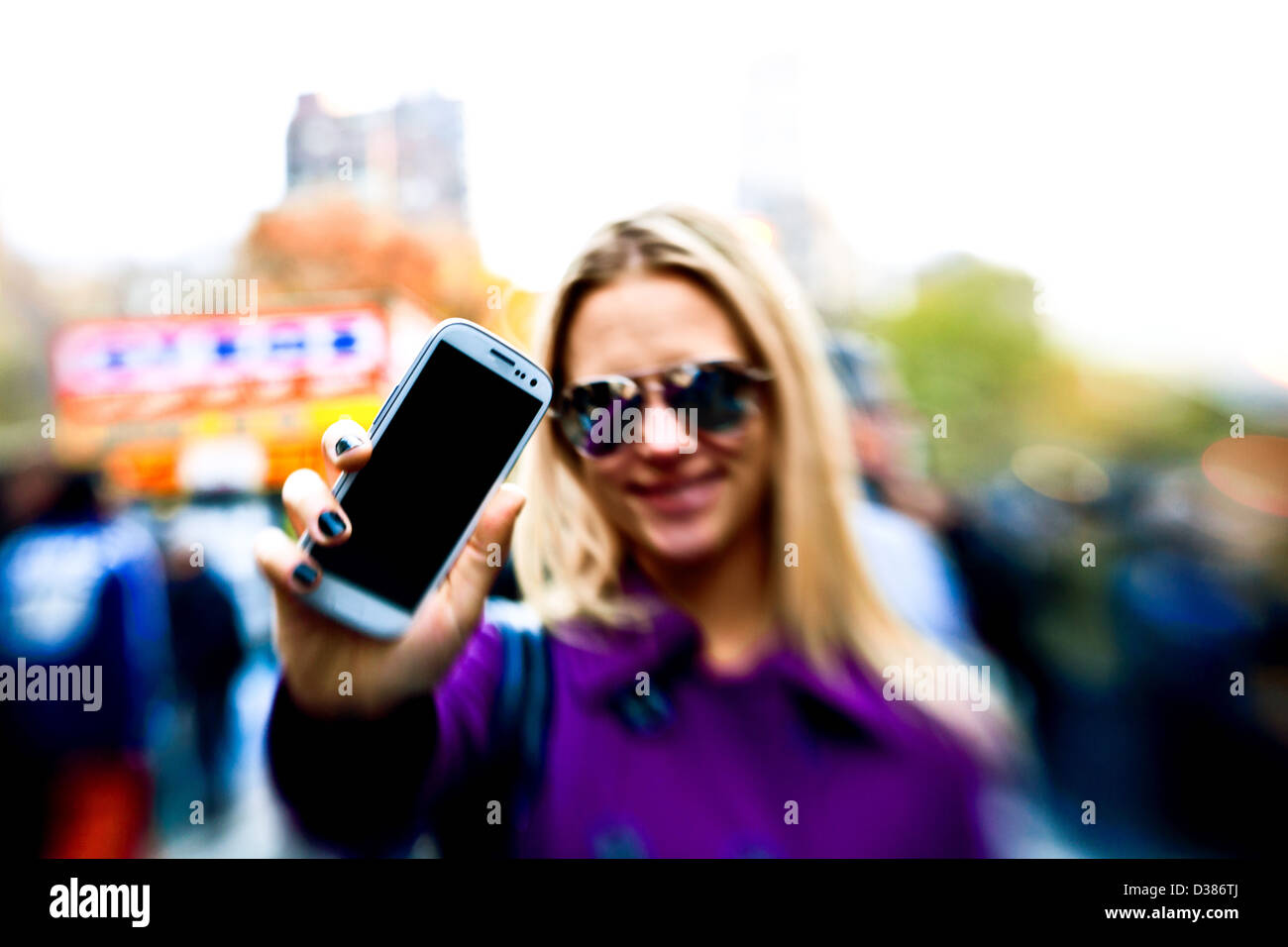Young Woman getting ready to use her phone at a street fair Stock Photo