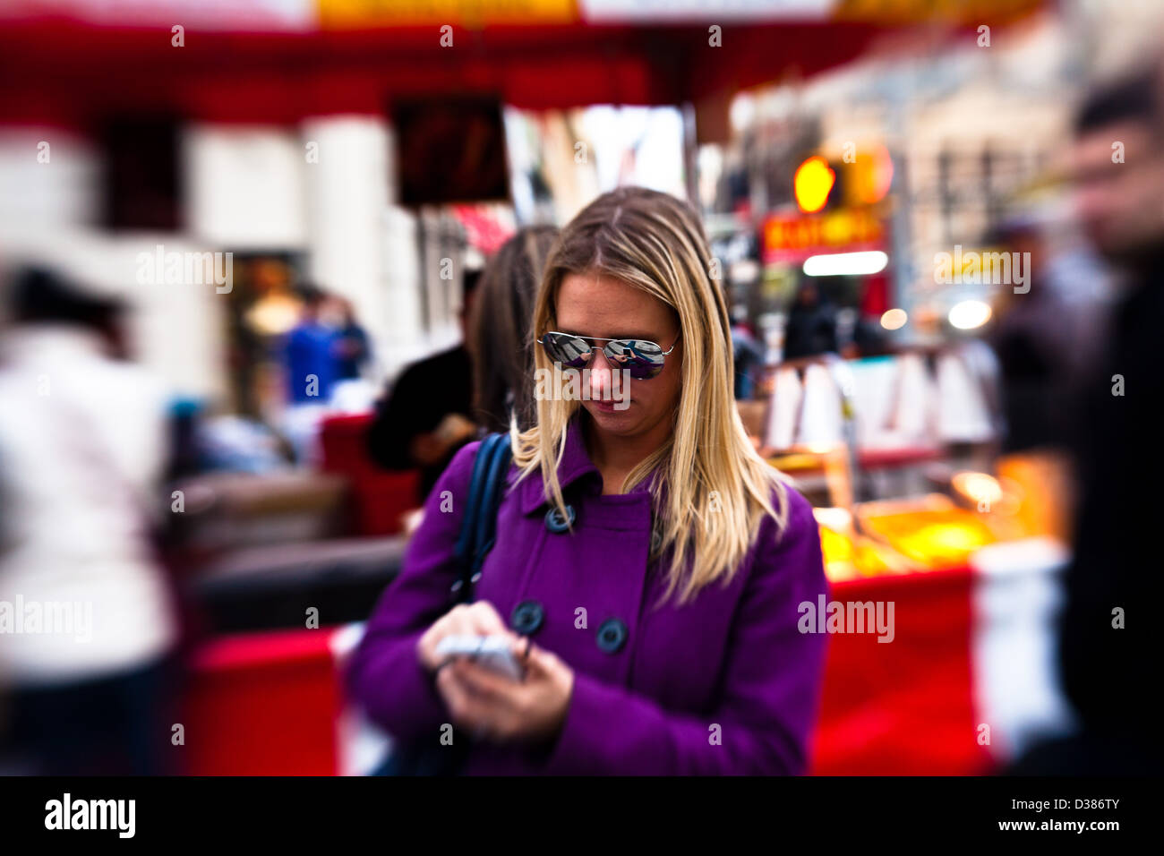 Young Woman getting ready to use her phone at a street fair Stock Photo