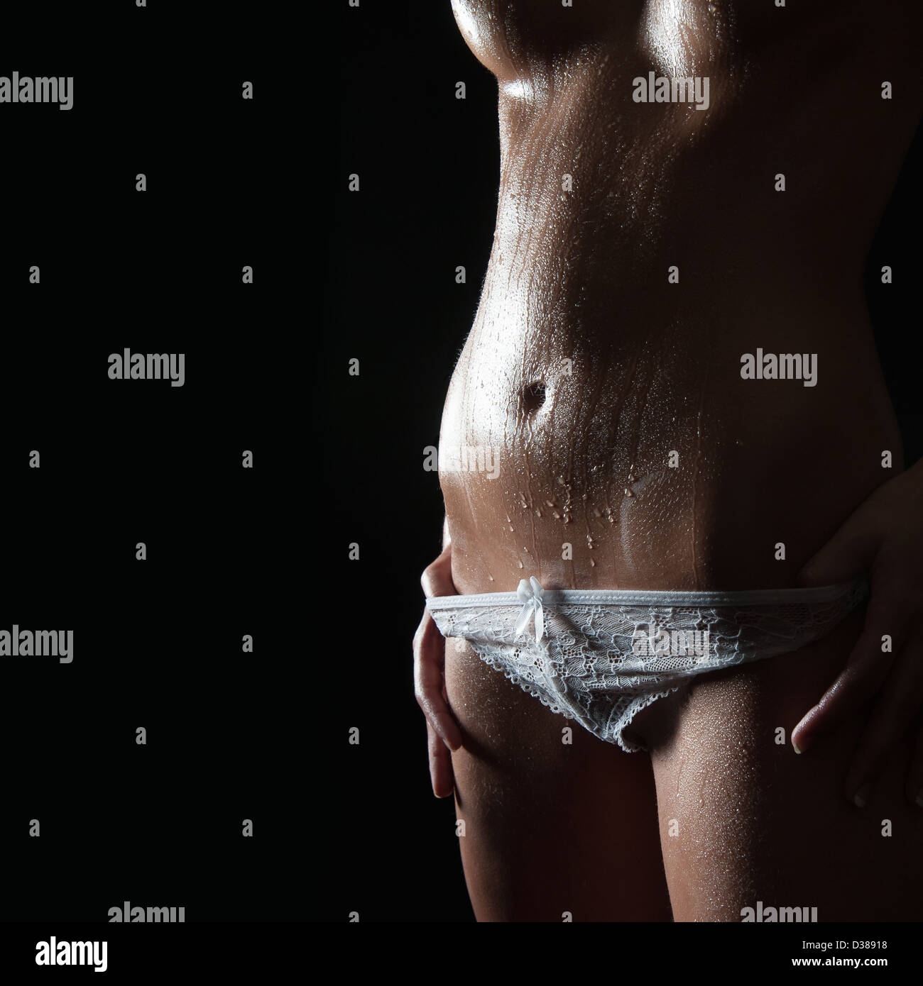 Nude slim woman with wet body in beautiful white panties, closeup in front  of black background Stock Photo - Alamy