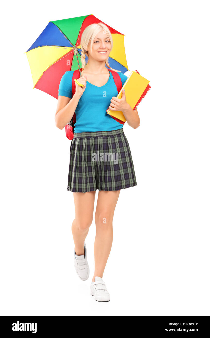 Full length portrait of a blond female student walking with umbrella and books isolated on white background Stock Photo