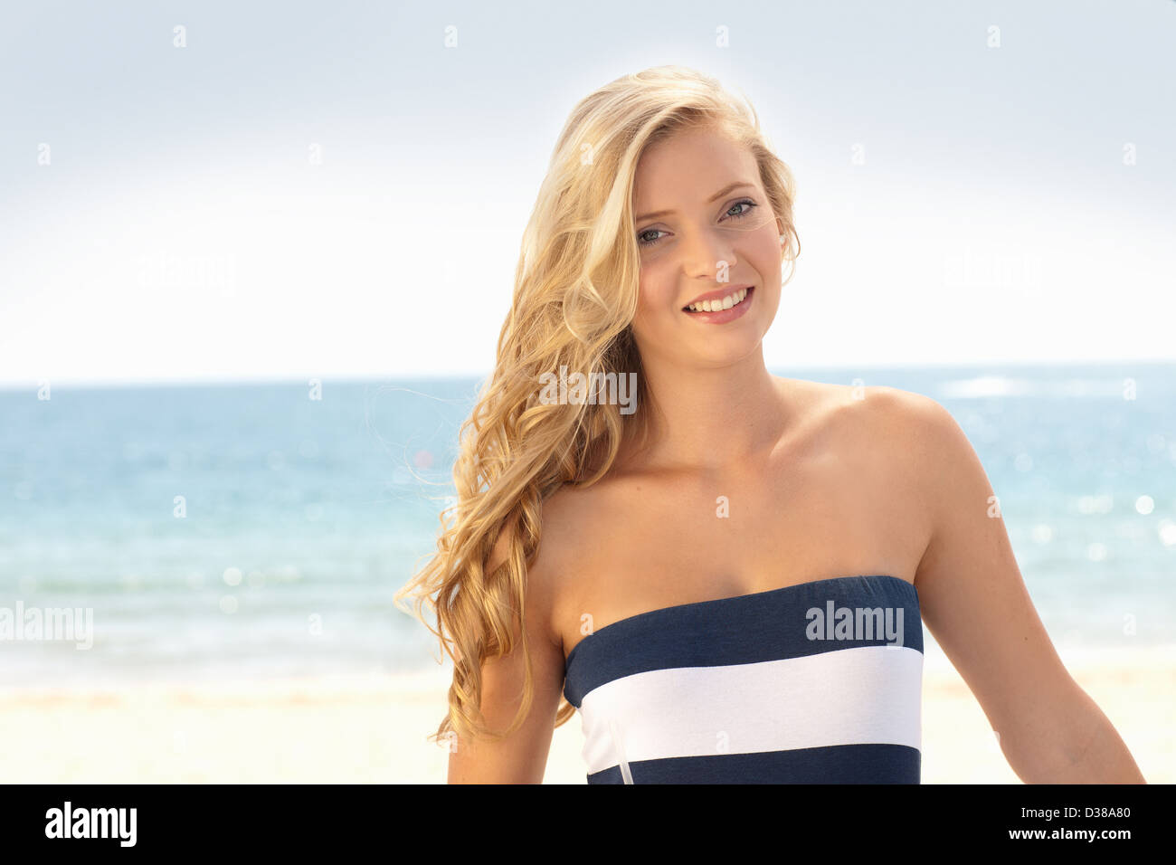 Smiling woman standing on beach Stock Photo - Alamy