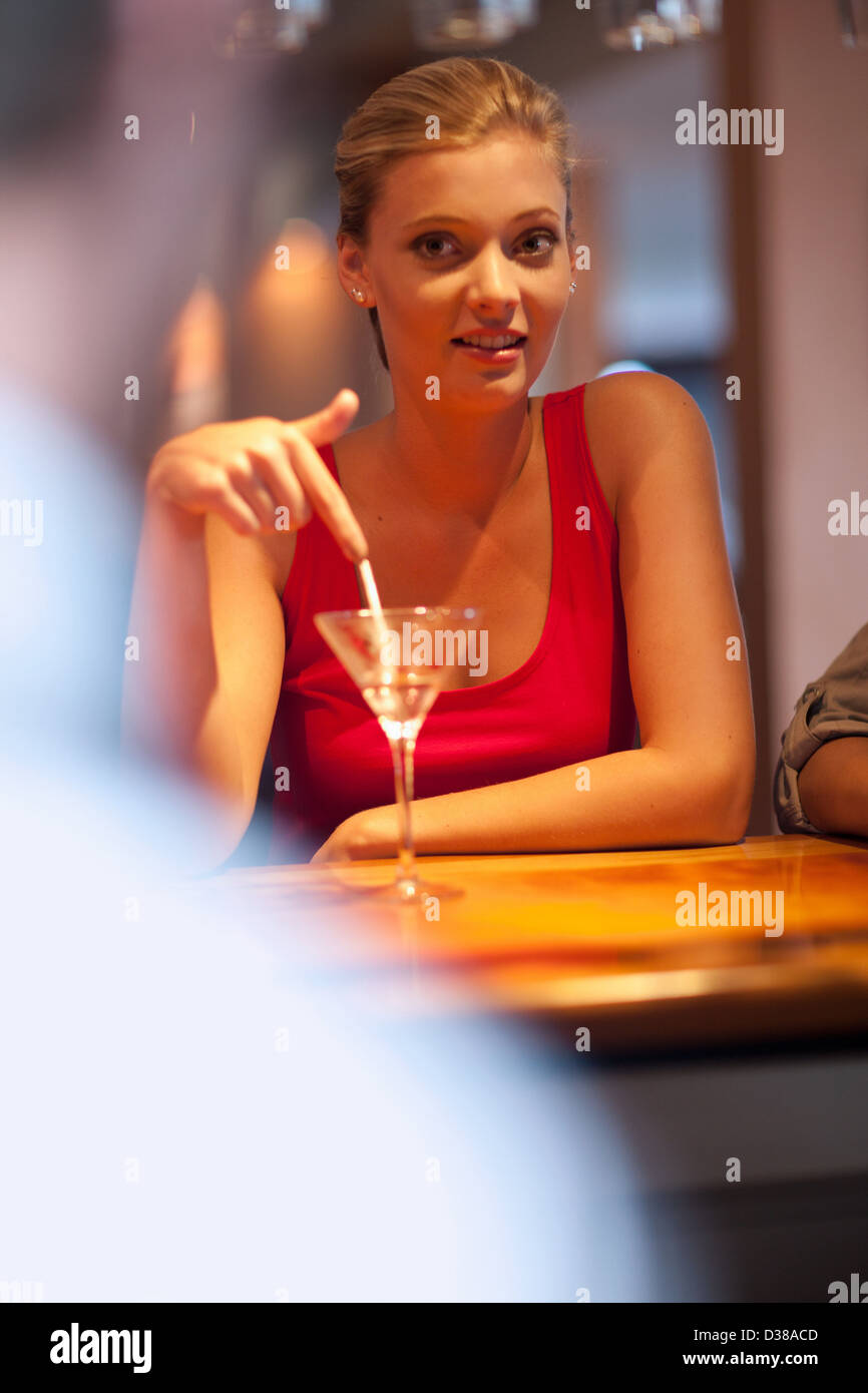 Woman ordering another drink at bar Stock Photo