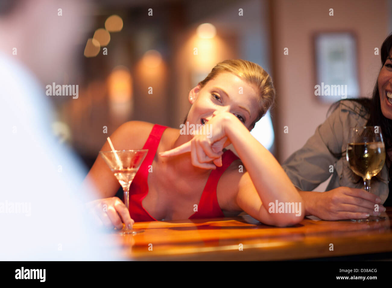 Woman ordering another drink at bar Stock Photo