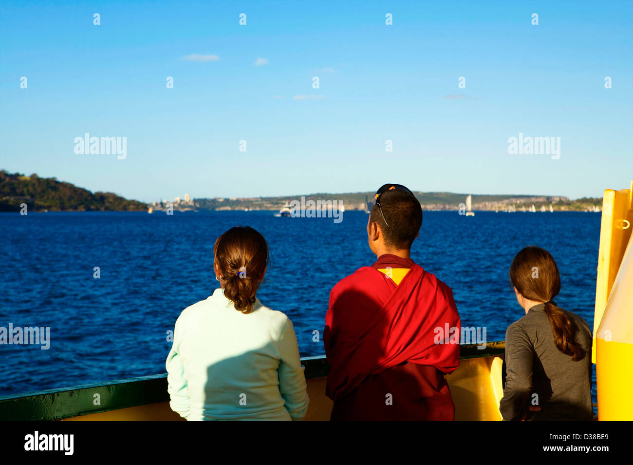 Two girls and a buddist monk look out from the deck of Sydney Ferry at the Sydney Harbor Stock Photo