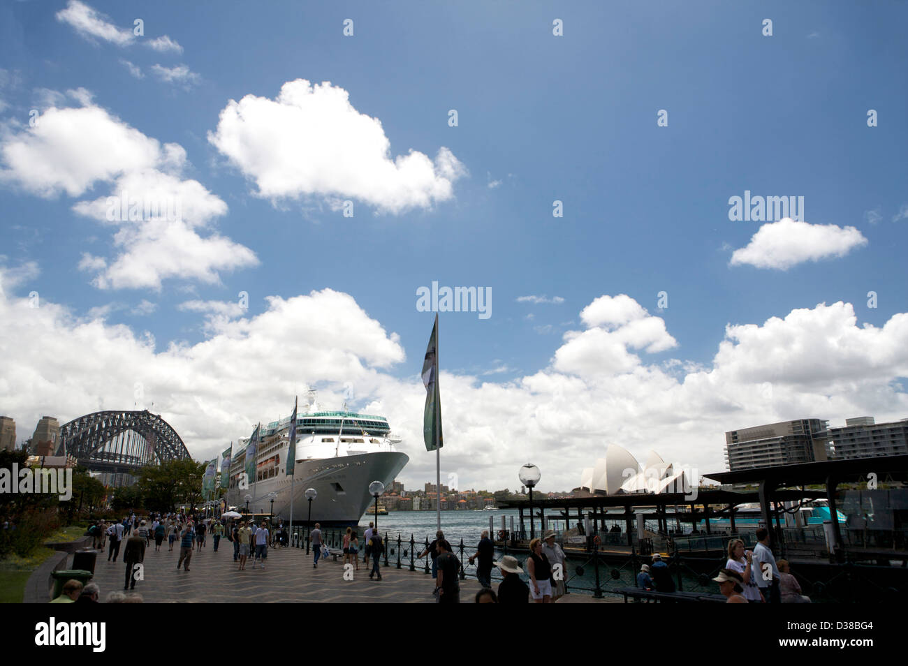 A large Ocean Liner docked in Sydney Harbour Australia, with a distant view of the Sydney Harbour Bridge and Sydney Opera House in the background. Stock Photo