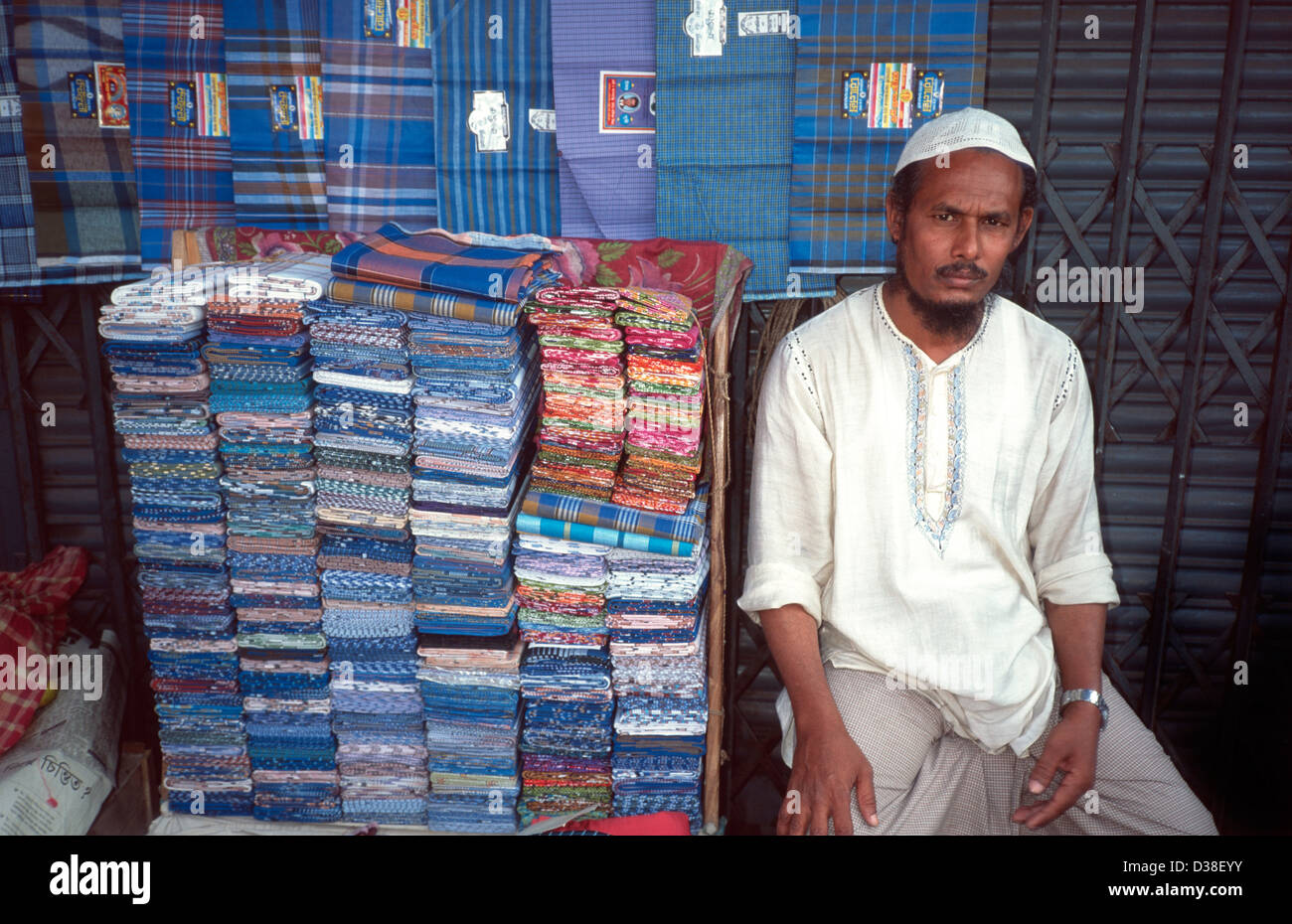 City street vendor sitting at his lunghi / sarong stall. Dhaka, Bangladesh Stock Photo