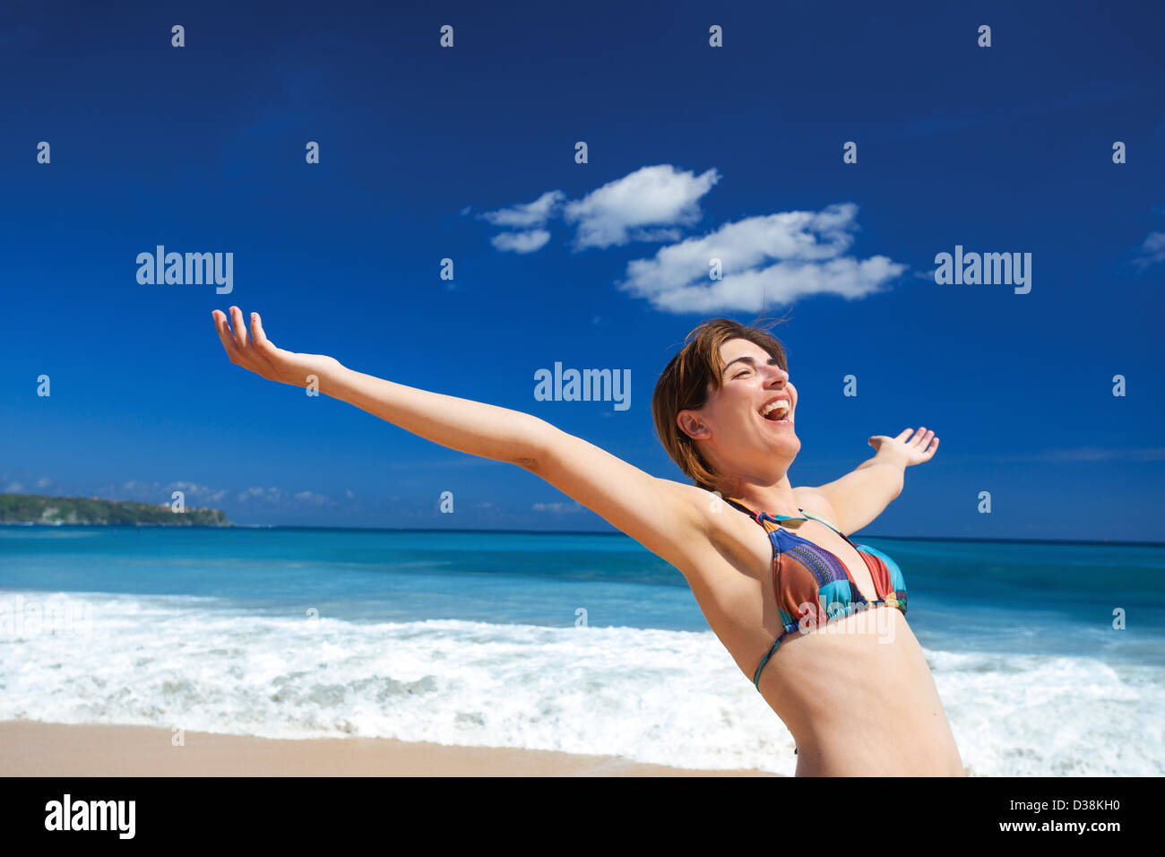 Beautiful young woman with arms open in a tropical beach enjoying the summer Stock Photo