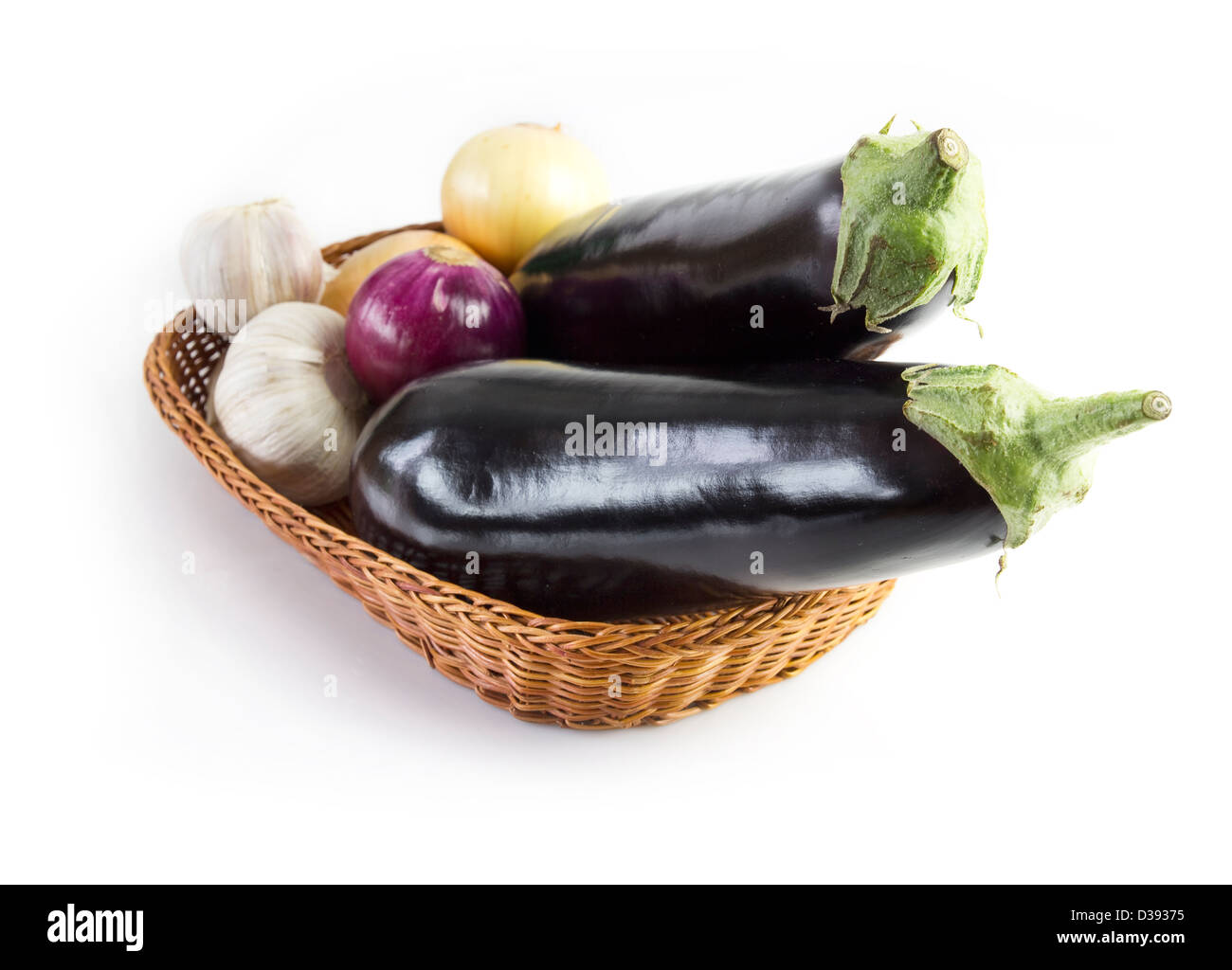 basket with eggplants, onions and garlic isolated on white background