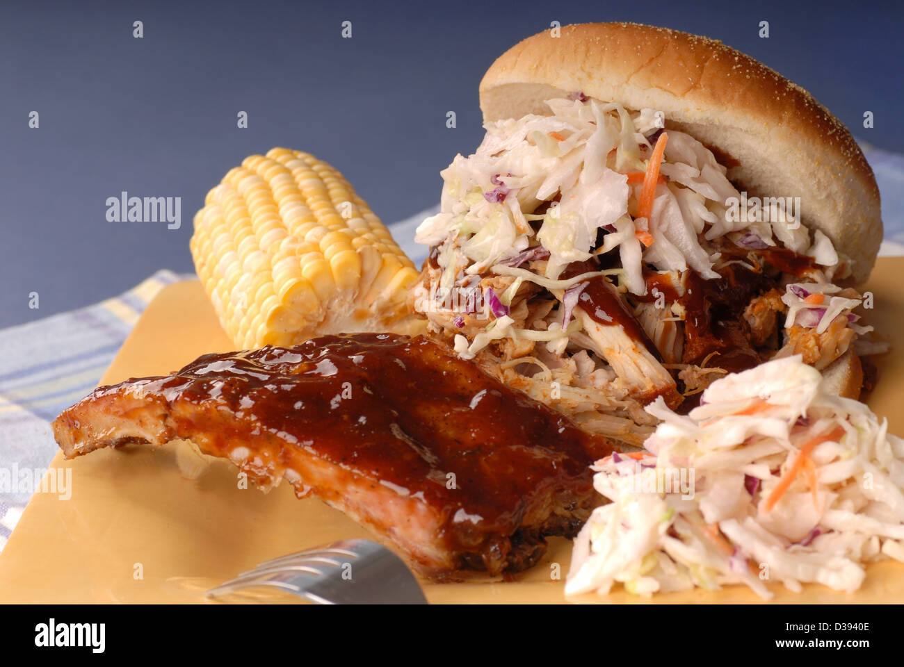 Pulled pork sandwich with cole slaw on it with ribs, corn and beans Stock Photo