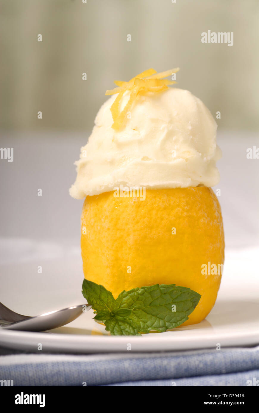 Lemon sorbet in a frozen lemon shell with mint Stock Photo