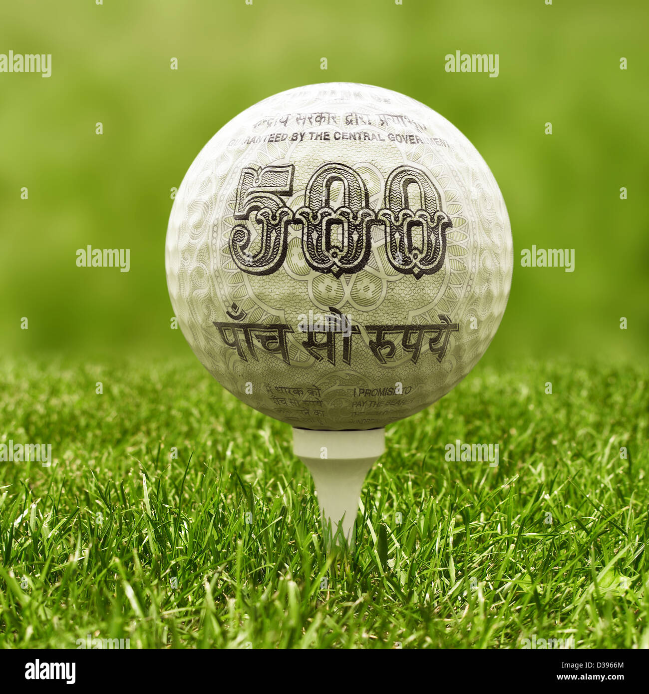 Closeup view of golf ball covered with Indian five hundred Rupee note