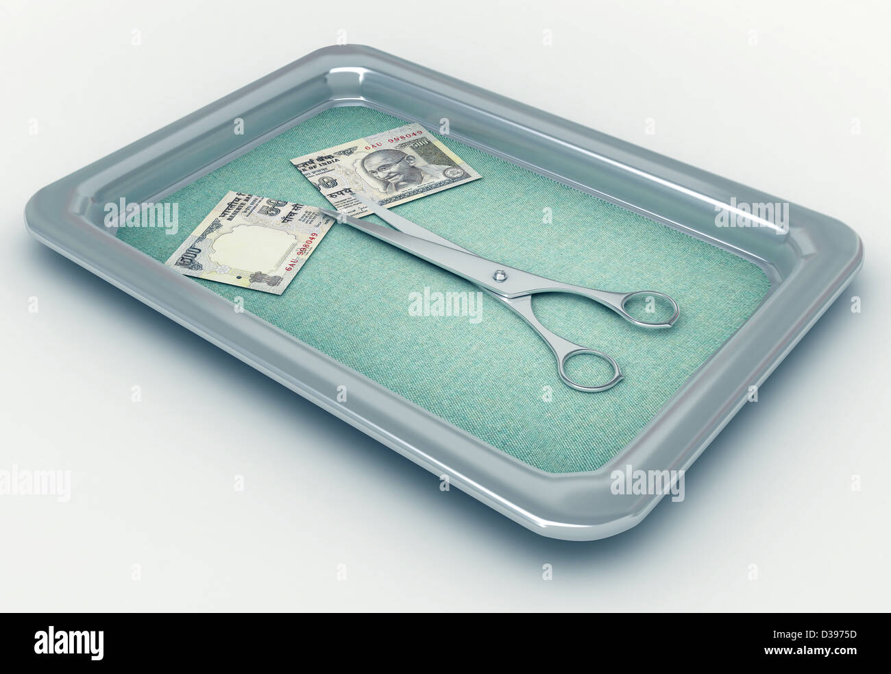 Conceptual shot of currency cut in half with scissors in tray depicting cost cutting Stock Photo