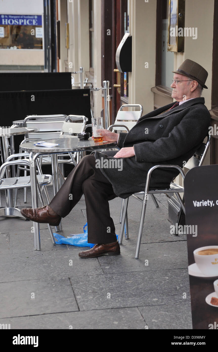 Senior citizen drinking alcohol in pavement cafe bar in Glasgow, Scotland, UK, Europe. Stock Photo