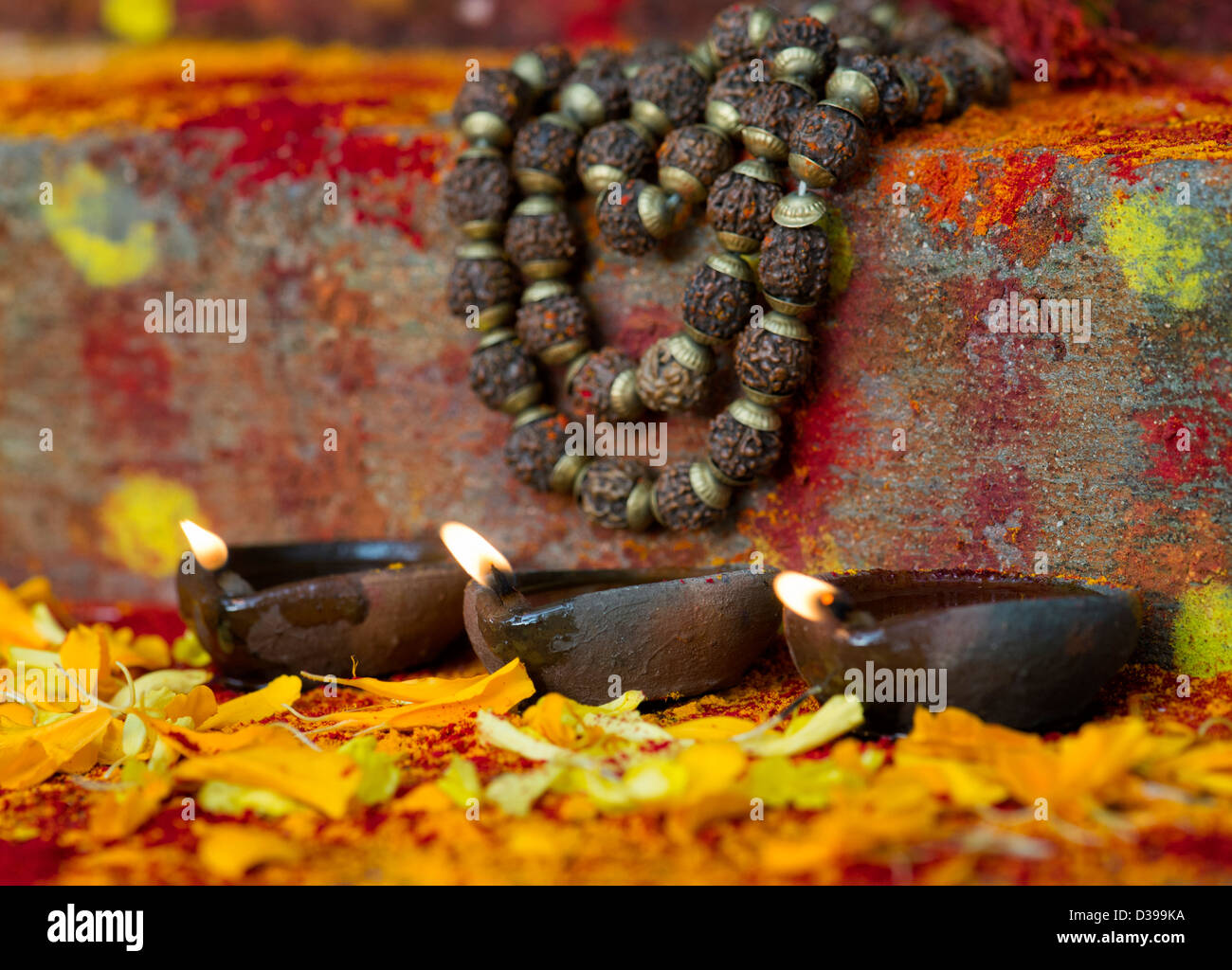 Oil Lamps and Indian Rudraksha / Japa Mala prayer beads on the steps of a rural indian village shrine / temple. India Stock Photo