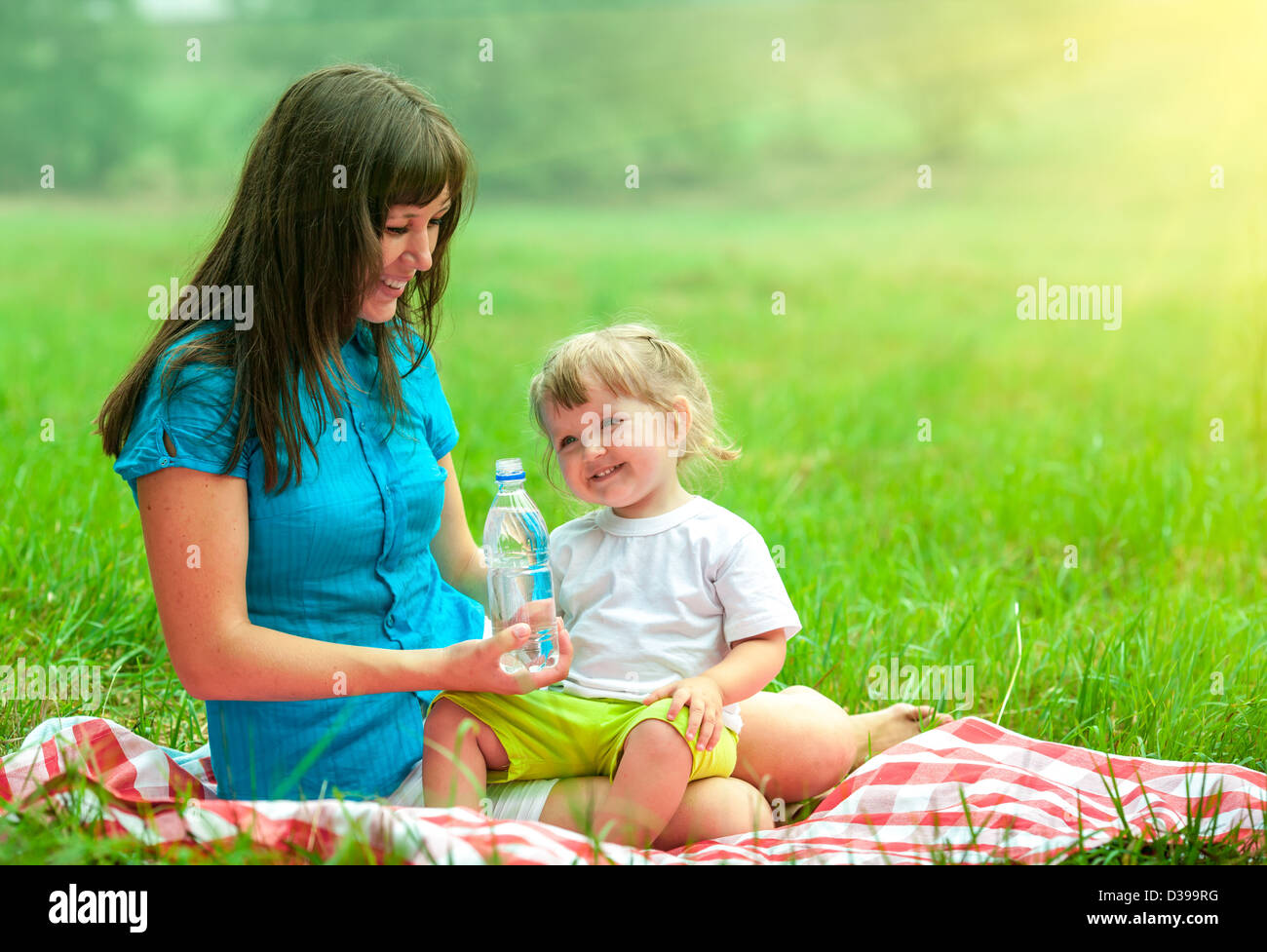 mother and daughter have picnic outdoor drinking water from plastic bottle Stock Photo
