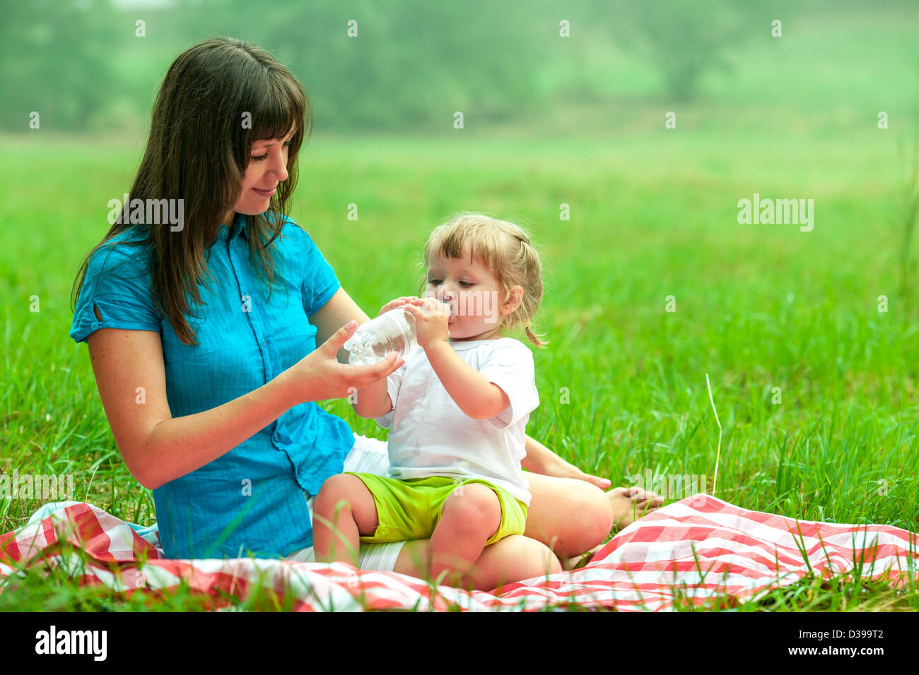 mother and daughter have picnic drinking water from bottle Stock Photo