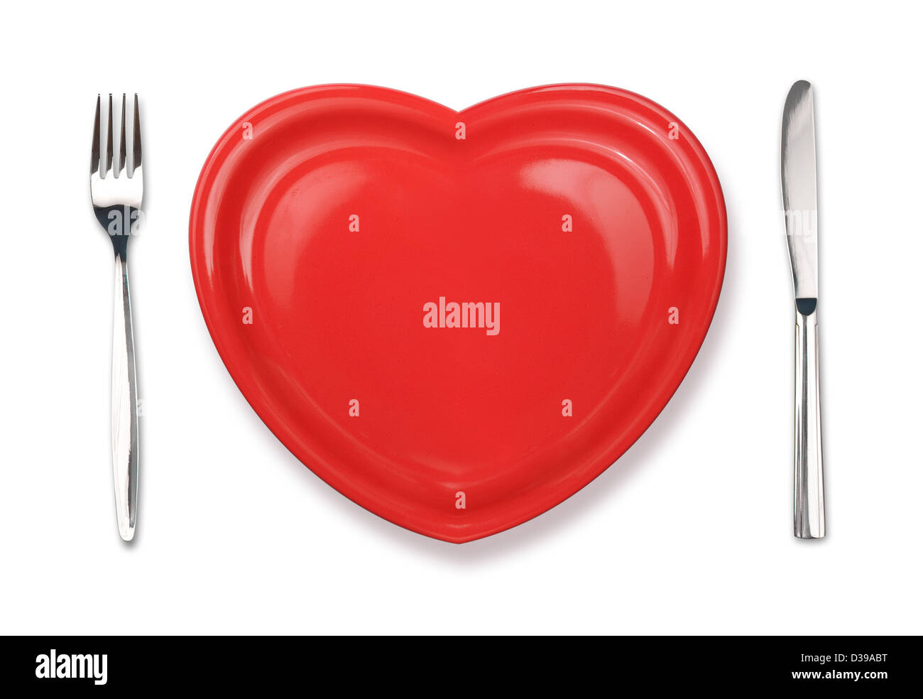 Knife, red plate in heart shape and fork isolated on white Stock Photo