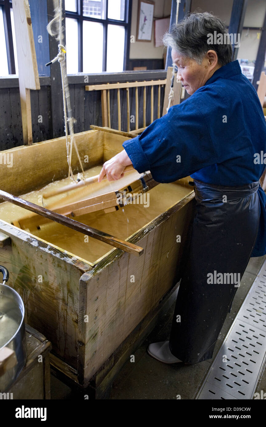 Woman making traditional washi Japanese paper by hand in a wooden tub. Stock Photo