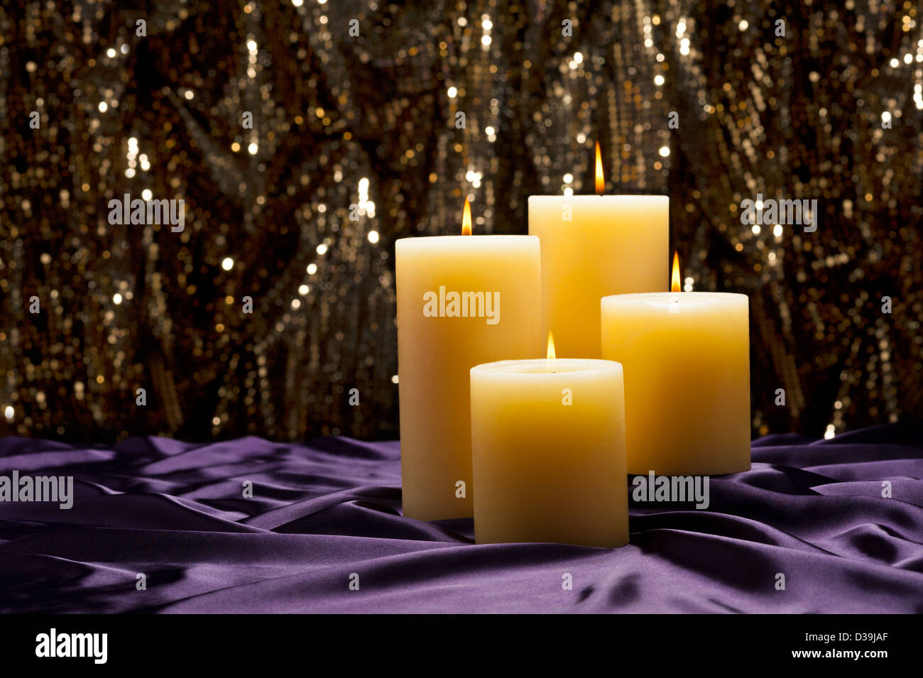 Four candles over purple velvet, with gold glitter background Stock Photo