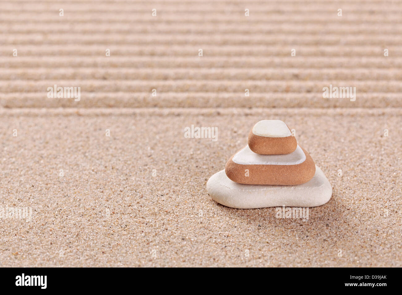 Three pebbles stacked on a raked sand zen garden. Stock Photo