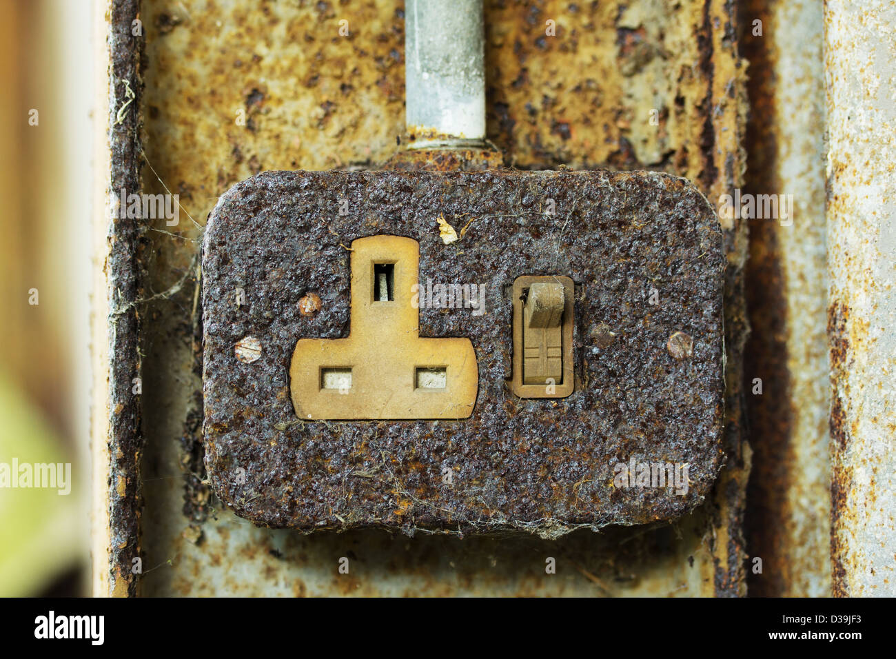Old rusty 3 pin plug socket on a rusty beam Stock Photo