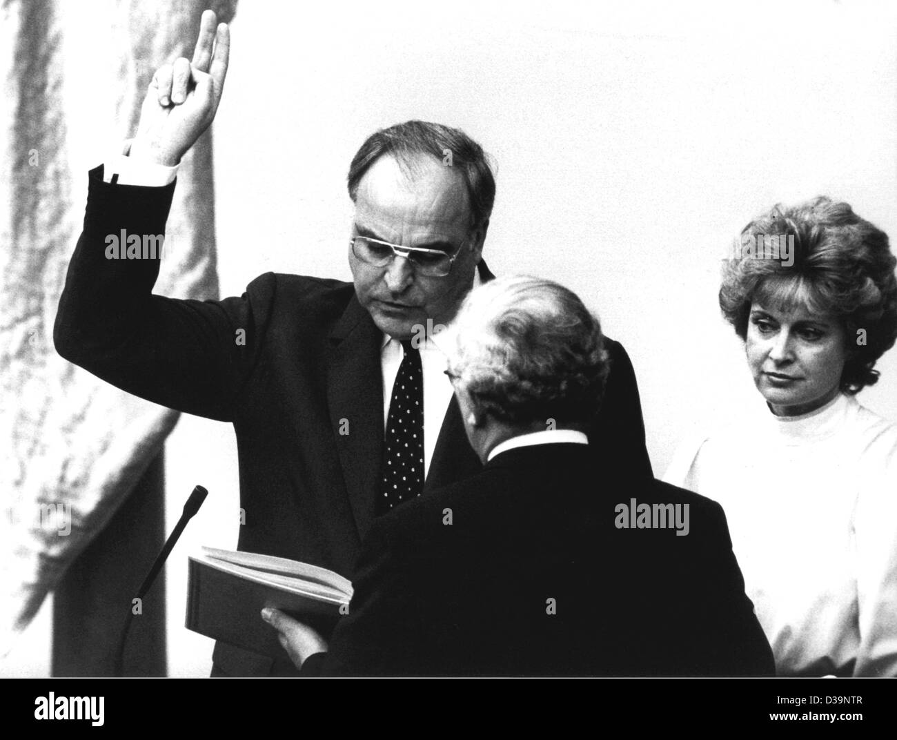 (dpa files) - After the general elections, Chancellor Helmut Kohl (L) is swearing in at the parliament in Bonn, 29 March 1983. Rainer Barzel, President of Parliament, is carrying out the ceremony. On the right: Michaela Geiger of the CSU. Stock Photo