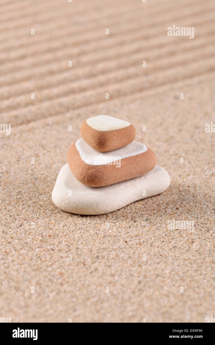 Three stones stacked on a raked sand zen garden. Stock Photo