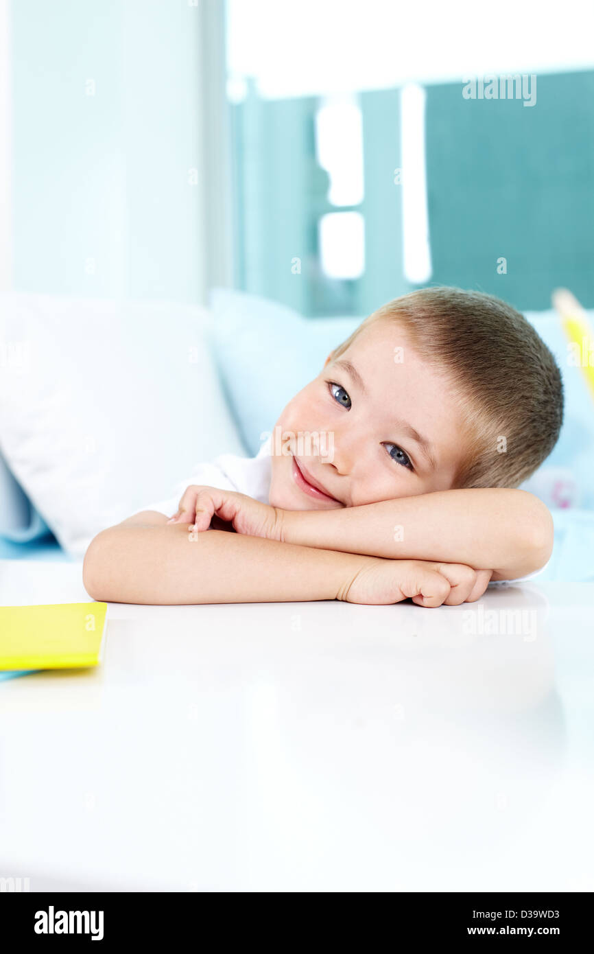 Smiling boy looking at camera while sitting by table Stock Photo - Alamy