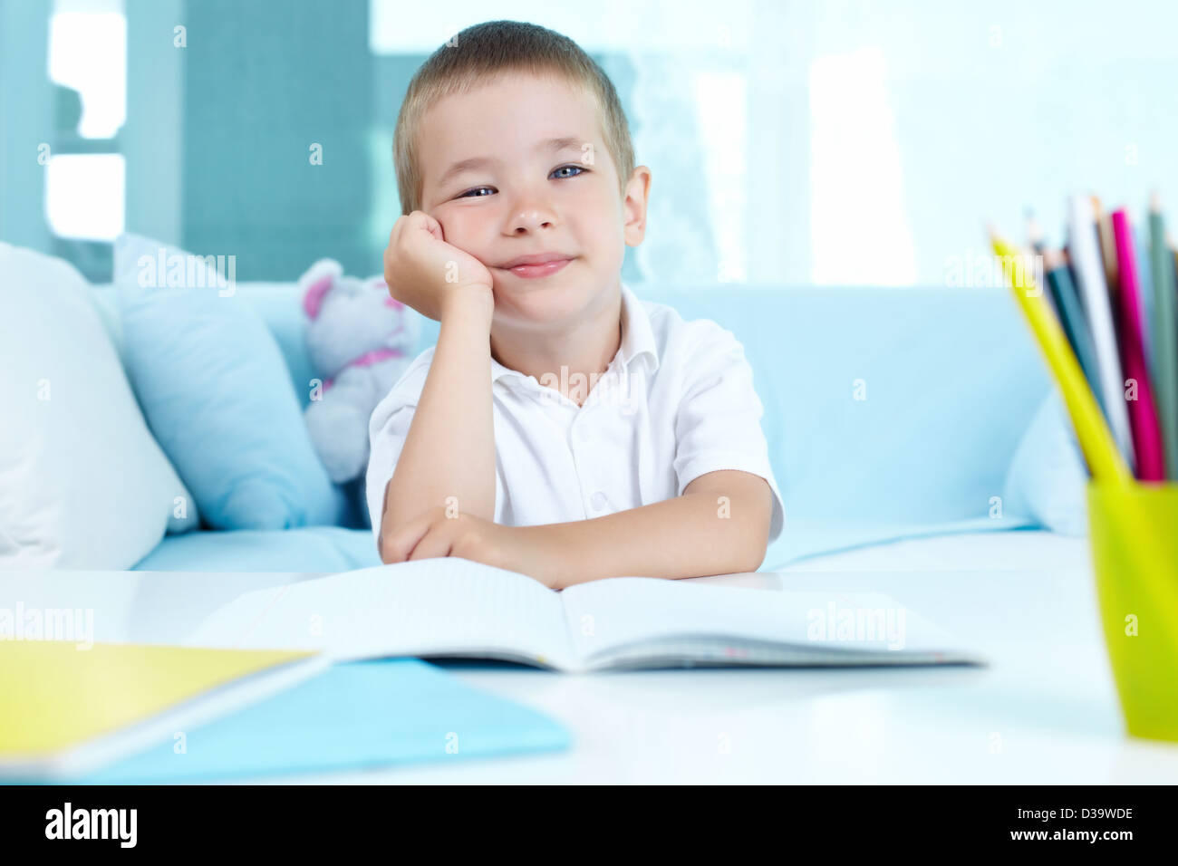 Smiling boy looking at camera while sitting by table Stock Photo - Alamy