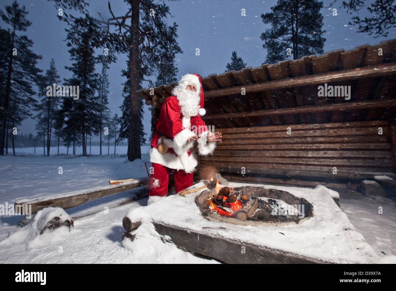 Man in father christmas costume by campfire, Lapland Stock Photo