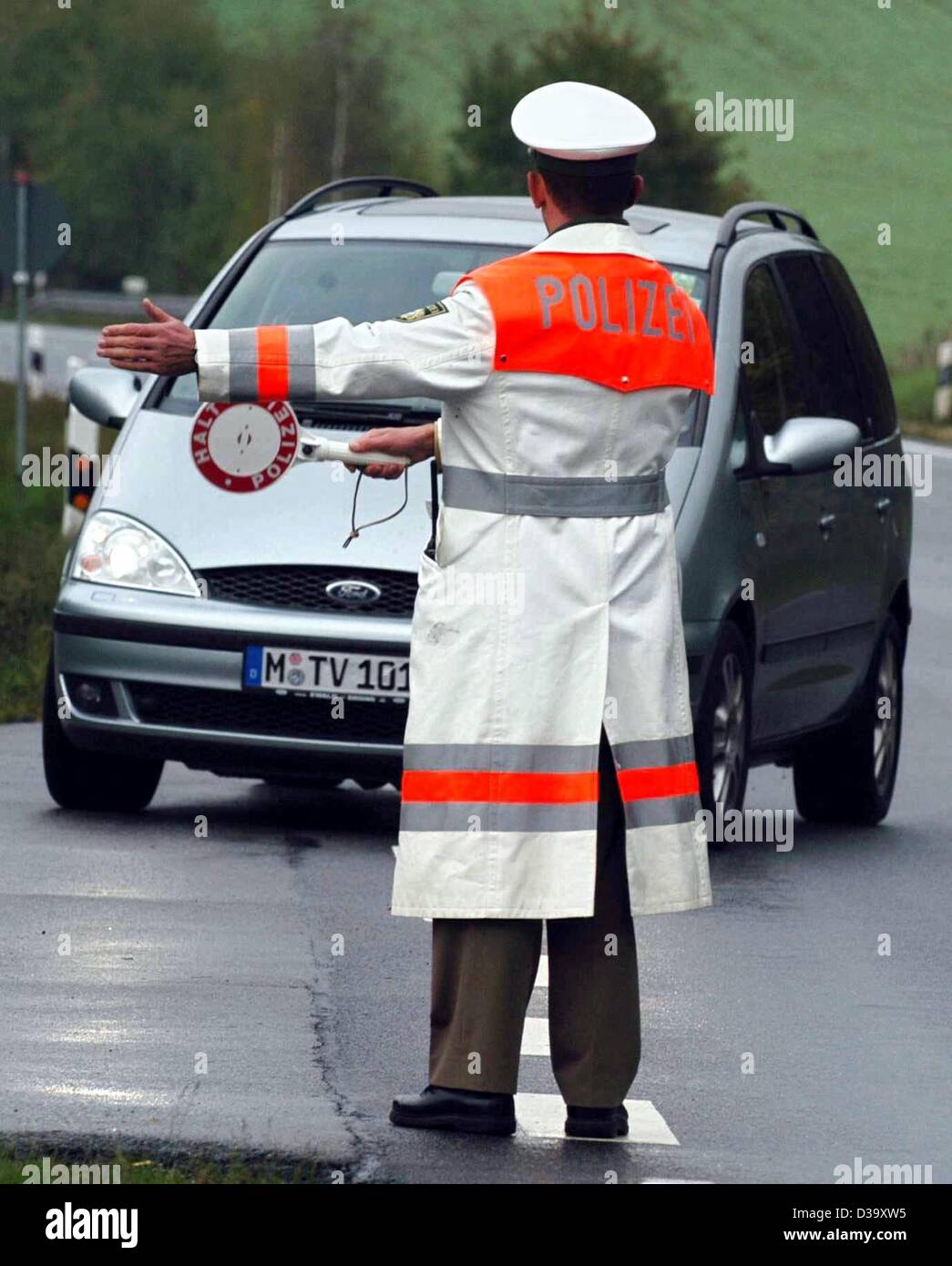 (dpa) - A police officer holds a scoop in his hand and indicates the driver of a car to pull over at a police checkpoint in Loitzendorf, Germany, 10 October 2003. The police in Bavaria has started an initiative to crack down on speeding drivers and to prevent any resulting accidents from careless dr Stock Photo