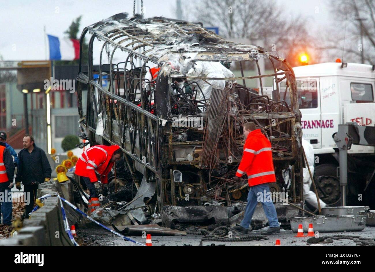 (dpa) - Rescue workers inspect the wreckage of a German coach which hit the central reservation and caught fire on the motorway from Brussels to Paris near Hensies, Belgium, 20 December 2003. Twelve people died in the crash, most of them German, and dozens more were injured. The bus was carrying 49  Stock Photo