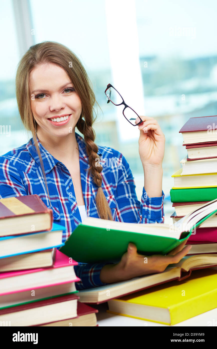 Portrait of diligent student looking at camera with open book in hands