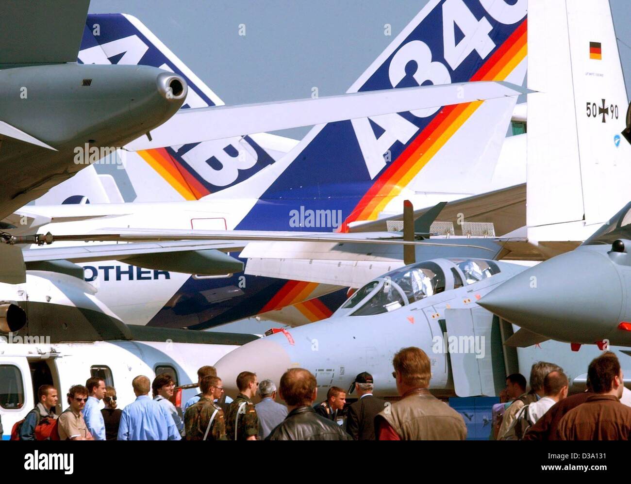 (dpa) - Visitors of the 6th International Aviation Fair ILA ('Internationalen Luft- und Raumfahrt-Ausstellung') are looking at several war planes and passenger planes of the Airbus group exhibited in Berlin-Schoenefeld, 8 May 2002. 1067 exhibitors from 40 countries were taking part. Stock Photo