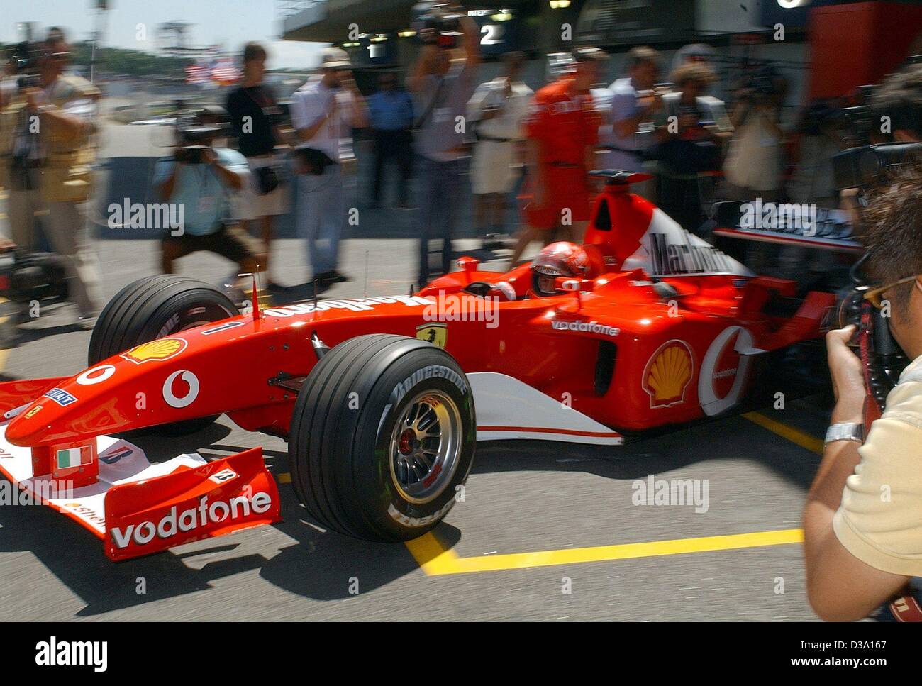 (dpa) - Michael Schumacher, German formula 1 champion, drives his new Ferrari F2002 in front of numerous photographers onto the racing track in Interlagos near Sao Paulo, 29 March 2002. Stock Photo