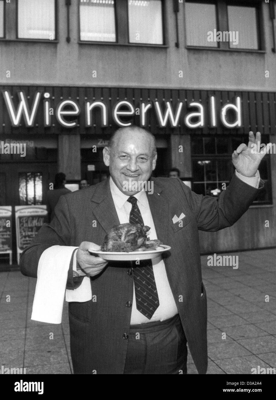 (dpa files) - The so called 'hendlkoenig' (chicken king) Friedrich Jahn acts as a waiter serving a fried chicken in front of one of his 'Wienerwald' chain restaurants, 16 February 1987. Stock Photo