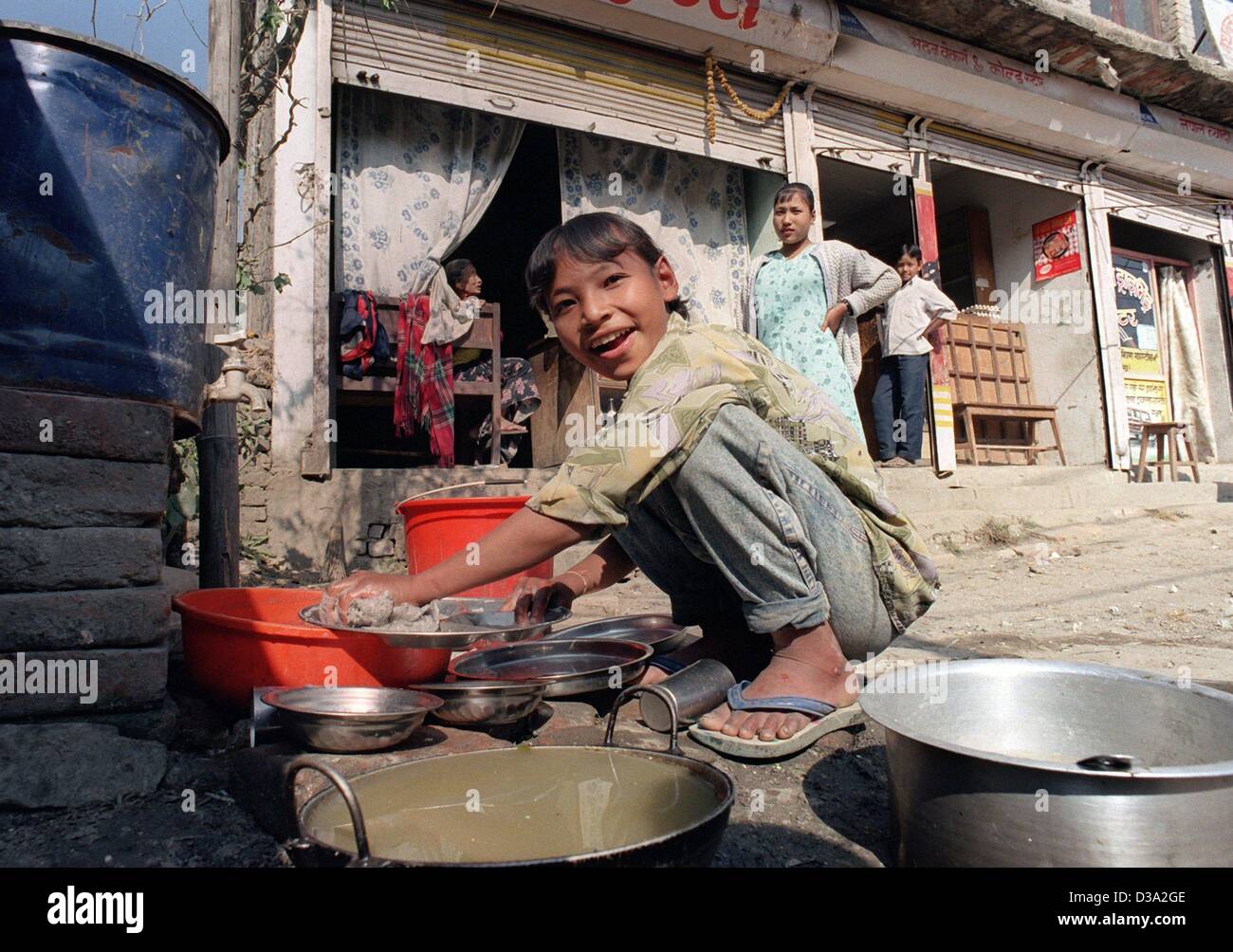 (dpa) A girl works as a dishwasher in the slums of Kathmandu in Nepal