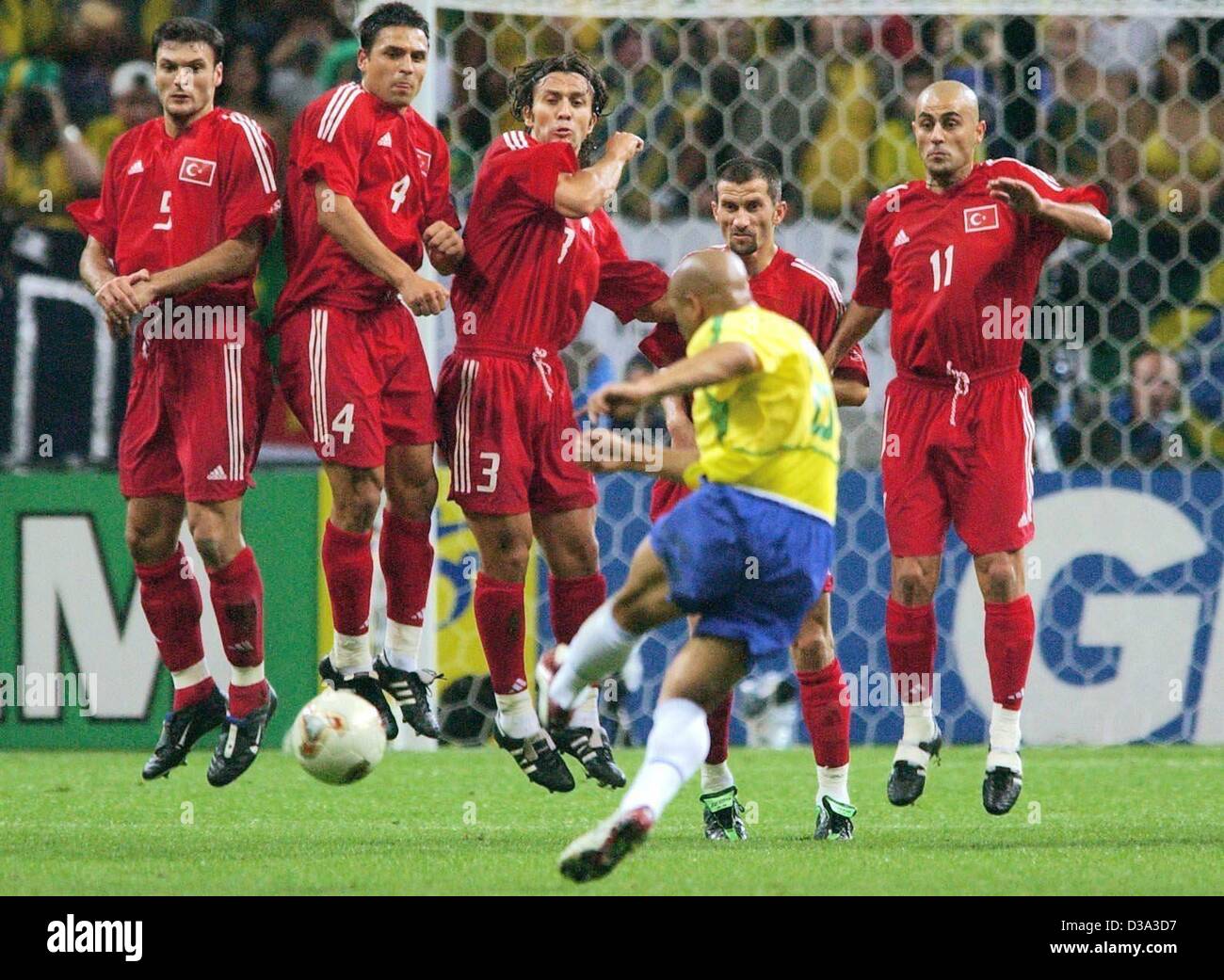 (dpa) - Brazilian defender Roberto Carlos (back view) shoots a flat free kick into a wall of jumping Turkish defenders (L-R:) Alpay Oezalan, Fatih Akyel, Buelent Korkmaz, Erguen Penbe and Hasan Sas during the semi final of the FIFA World Cup in Saitama, Japan, 26 June 2002. The match ended 1:0 for B Stock Photo