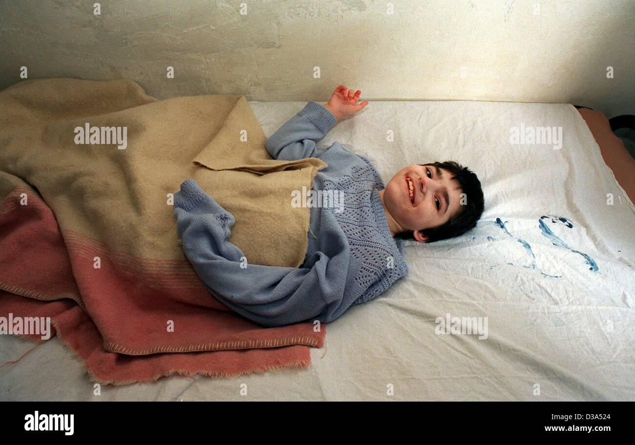 (dpa files) - A severely handicapped child smiles at the photographer in the UNICEF home for disabled 'Negru Voda' in Romania, 3 June 2001. The home houses 90 disabled children and 86 mentally or physically disturbed adults. Six nurses are working in shifts to wash and feed the disabled. Stock Photo