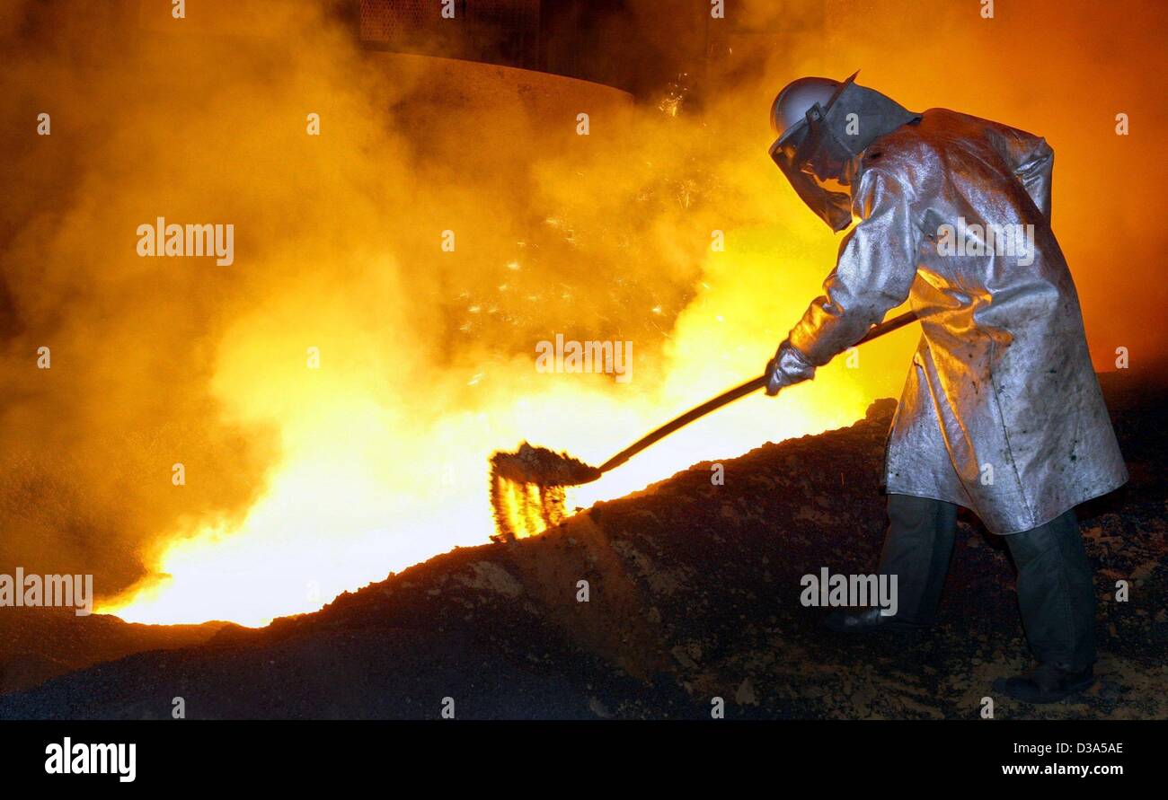 (dpa) - A worker in safety gear is shoving sand onto the 1470 Celsius degree hot iron in a blast furnace at the Salzgitter steel mill in the city of Salzgitter, Germany, 29 April 2002. Stock Photo