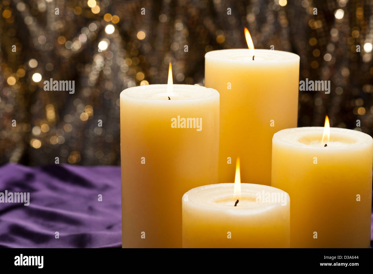 Four candles over purple velvet, with gold glitter background Stock Photo