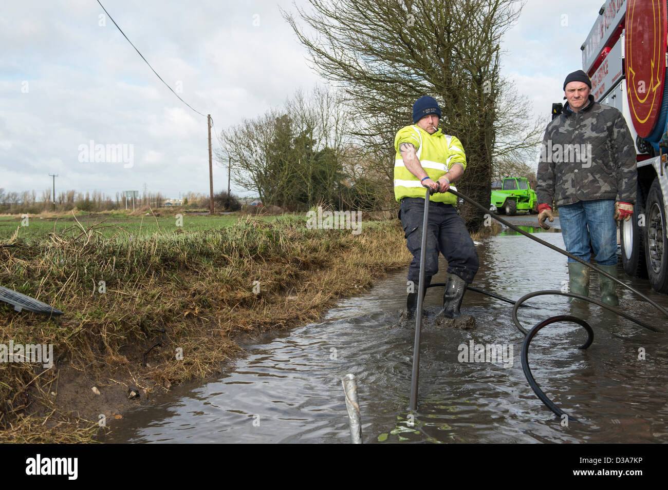 A worker clearing the blocked drains in a country lane as a build up of silt has caused longterm flooding and road closures. Stock Photo