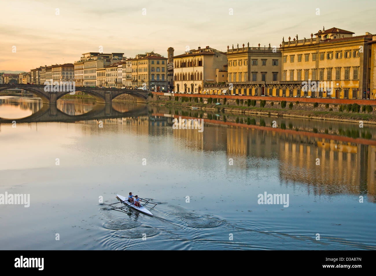 Two female  rowers on the River Arno in central Florence, Italy, rowing towards the Ponte alla Carraia and the Lugarno Corsini. Stock Photo