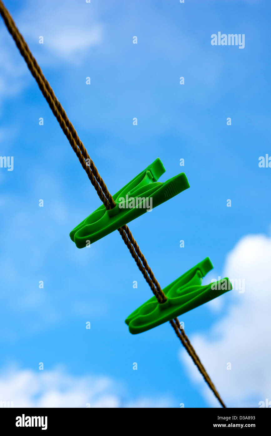 Two green peg on a washing line, against a cloudy blue sky. Stock Photo