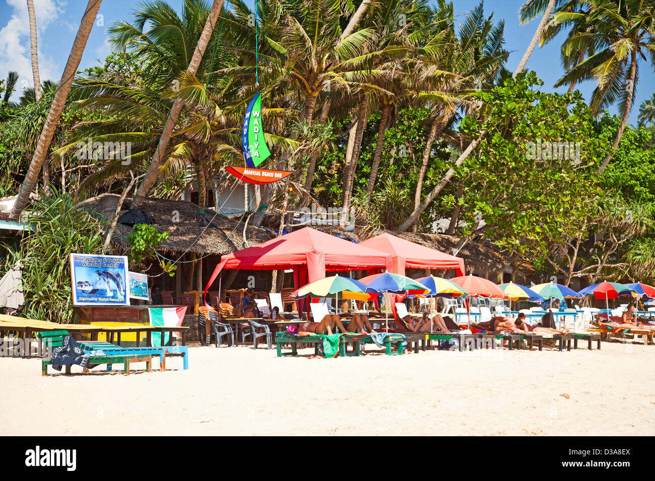 Tourists lying under parasols on the beach at Mirissa, sourthern Sri