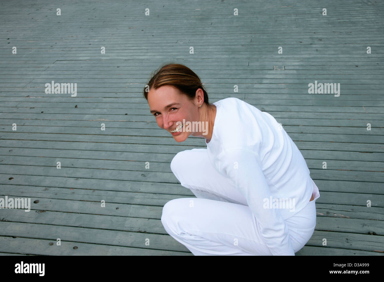 Woman crouching on wooden deck Stock Photo