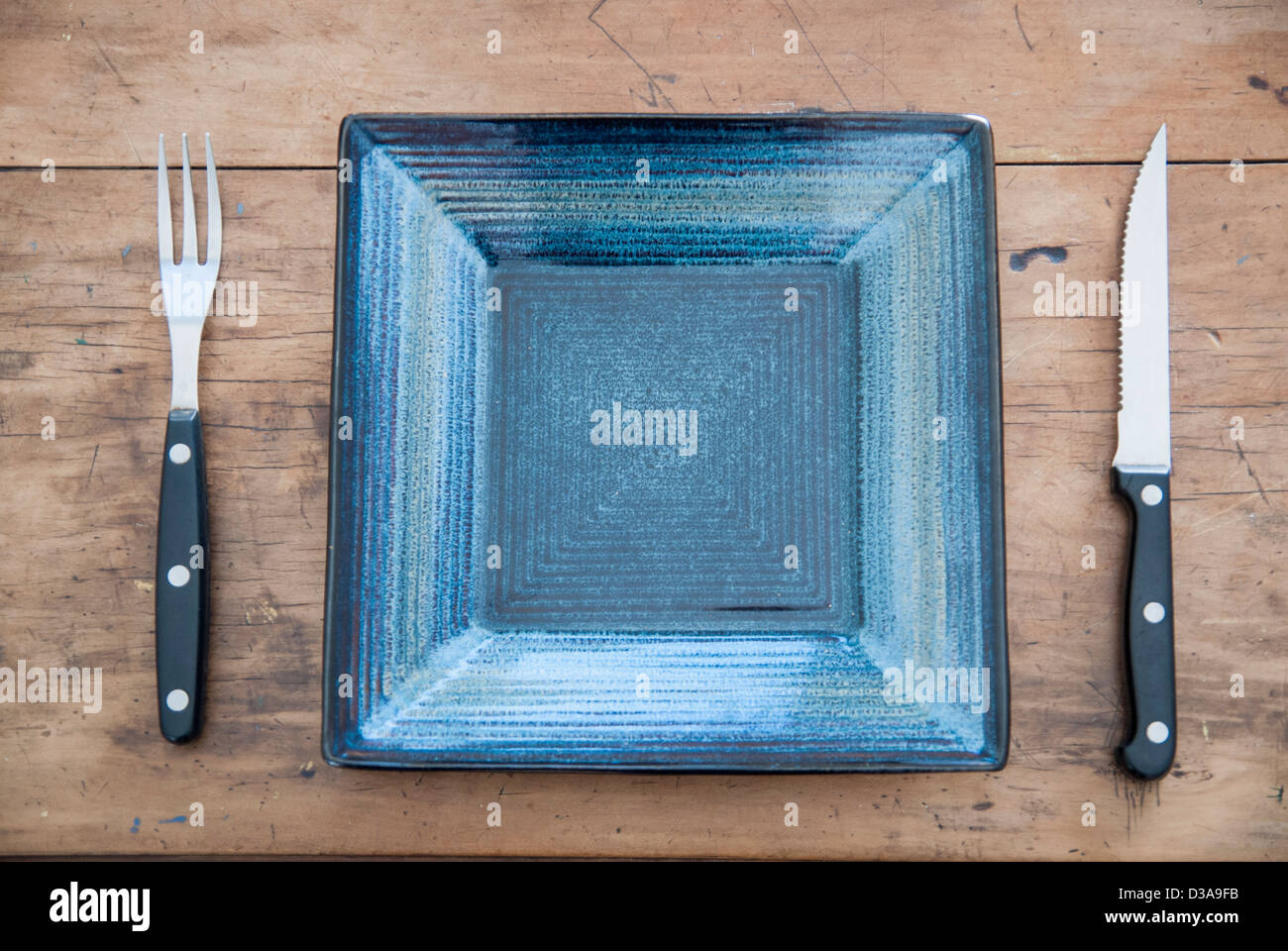 Empty plate, knife and fork on table Stock Photo - Alamy