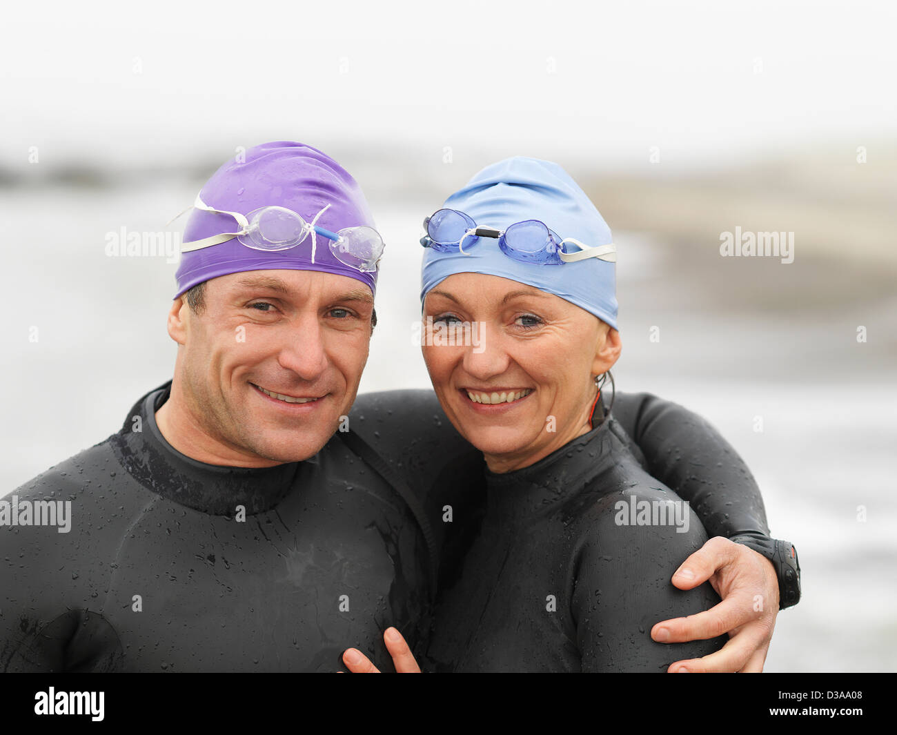 Divers smiling together on beach Stock Photo