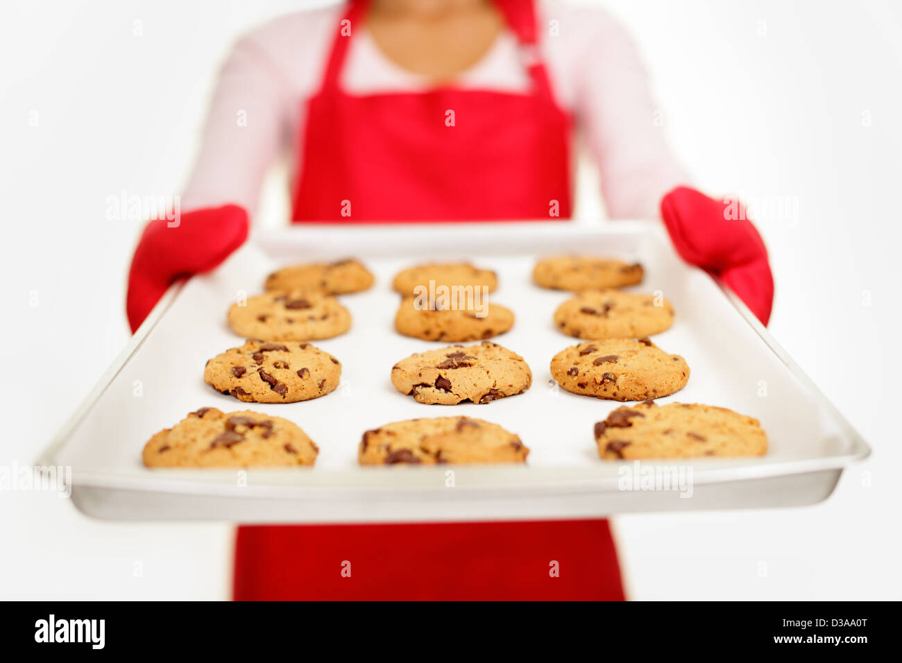 Young mixed race woman showing tray with fresh baked chocolate chips
