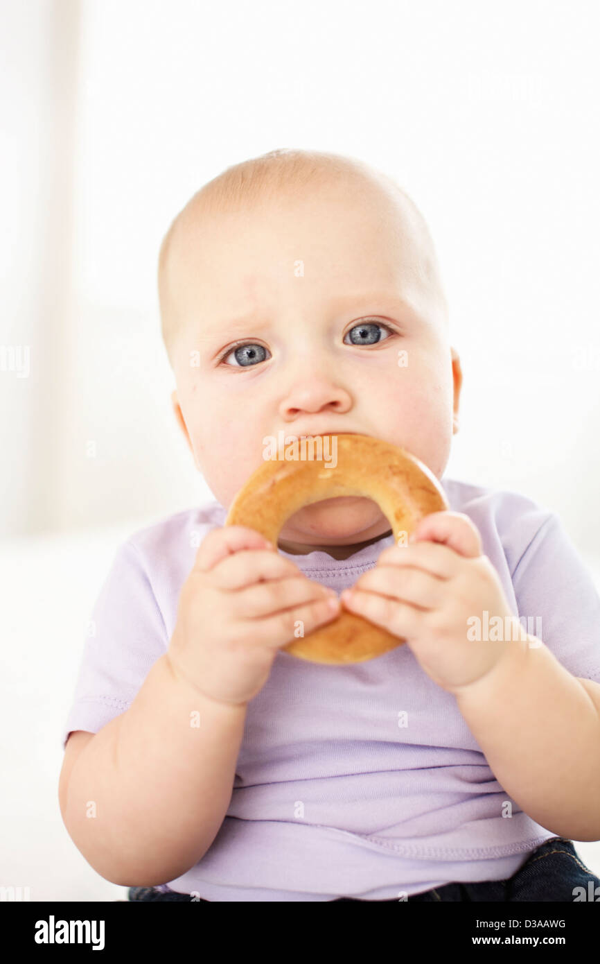 Baby girl eating bagel Stock Photo Alamy